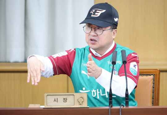 Daejeon Mayor Lee Jang-woo wears a Hanwha Eagles cap and a Daejeon Hana Citizen uniform as he presides over a weekly meeting. [DAEJEON METROPOLITAN GOVERNMENT] 