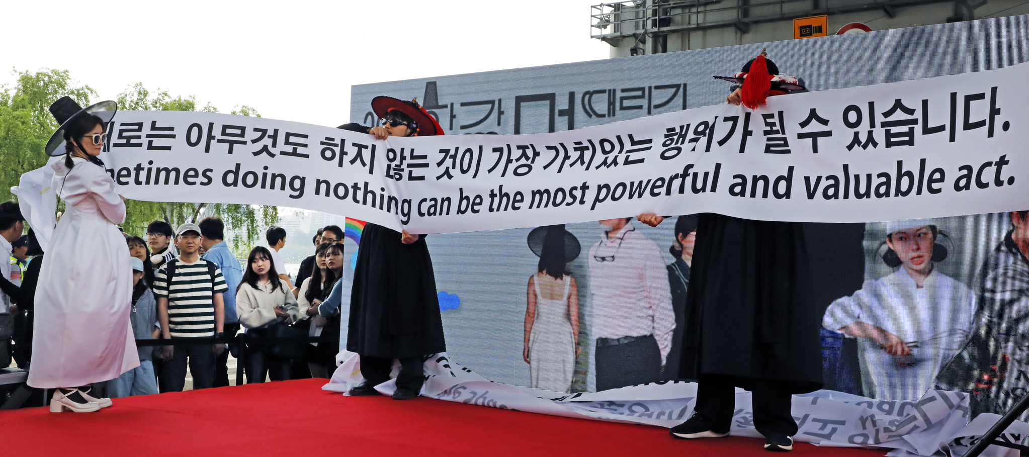 Contemporary performance artist Woopsyang, far left, unfurls a banner explaining the initiative of the Hangang Space-out Competition at Jamsu Bridge in Seocho District, southern Seoul, on May 11. [PARK SANG-MOON]