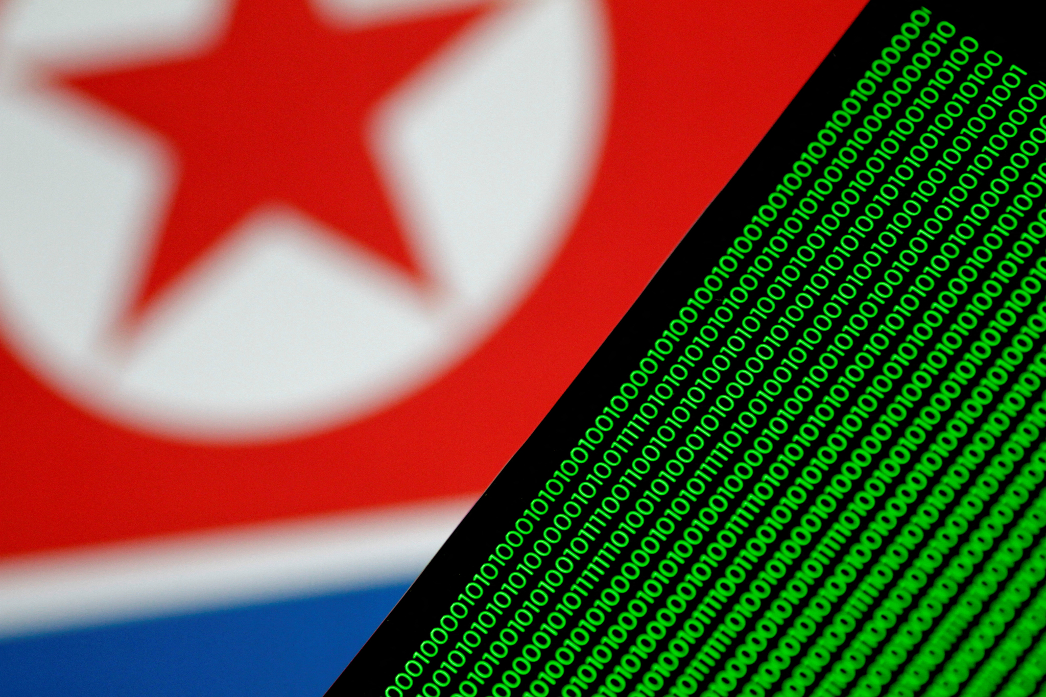 Binary code is seen on a screen against a North Korean flag in this illustration from Nov. 1, 2017. [REUTERS/YONHAP]