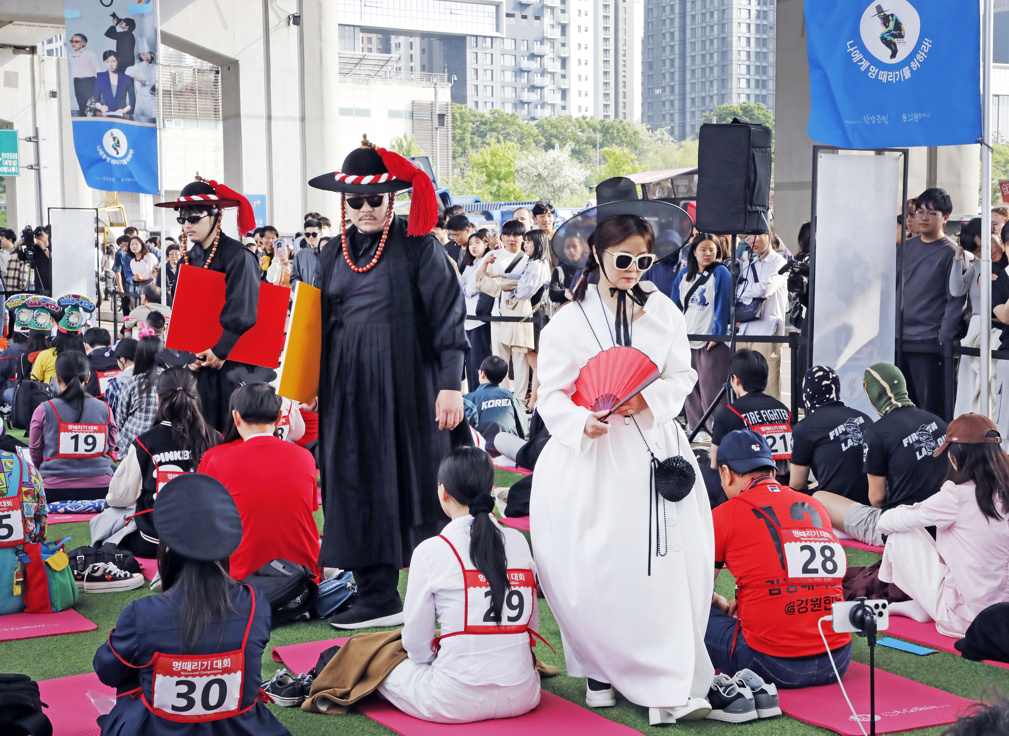 Contemporary performance artist and founder of the Space-out Competition Woopsyang, right, and staffers dressed as satto, or local officials of the Joseon Dynasty, walk among contestants participating in the Hangang Space-out Competition at Jamsu Bridge, in Seocho District, southern Seoul, on May 11. [PARK SANG-MOON]