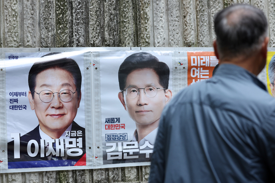 A pedestrian walks by posters of presidential election candidates at a bus station in Gwangju on May 15. [YONHAP] 