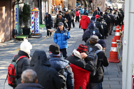 Older people wait in line to receive free meals at a soup kitchen near Tapgol Park in Jongno District, central Seoul, on Dec. 24, 2024. [YONHAP] 