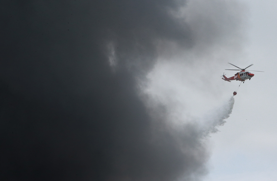 A helicopter tries to put out a fire at the Kumho Tire factory in Gwangju on May 17. [JOONGANG ILBO]
