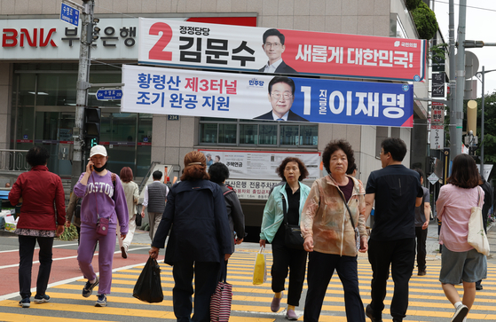 Pedestrians walk under banners displaying presidential candidates in Busan on May 19 ahead of the presidential election. [JOONGANG ILBO]