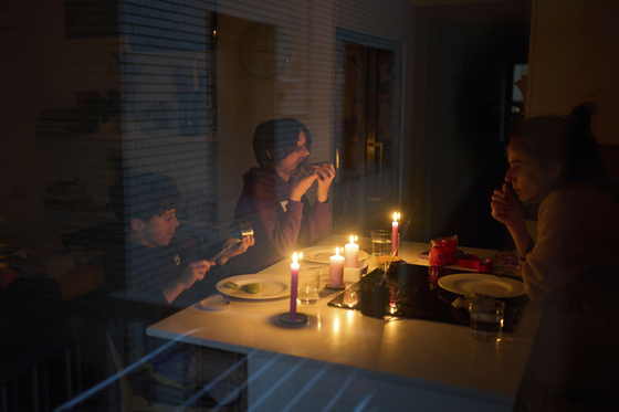A family eats a snack by candlelight during a blackout in Barcelona, Spain, on April 28. [AP/YONHAP]