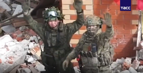 A North Korean soldier, left, and a Russian soldier wave after a successful joint operation against Ukrainian forces in an image released by Russia's TASS news agency on April 29. [TASS/YONHAP]