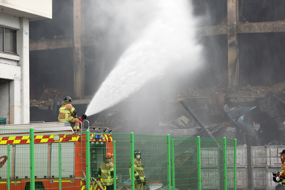 A firefighter sprays water to suppress dust and smoke at Kumho Tire’s Gwangju plant in Gwangsan District on May 20. [YONHAP] 