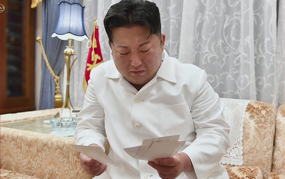 In this image captured from a documentary about Hyon Chol-hae, former senior advisor to the Ministry of National Defense and Marshal of the Korean People’s Army, North Korean leader Kim Jong-un cries while reading letters exchanged with Hyon [YONHAP]