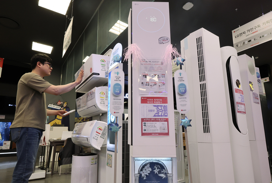 A shopper checks out an air conditioner at the Electro Mart inside the Emart Cheonggyecheon branch in Jung District, central Seoul, on May 21. Demand for seasonal appliances like air conditioners and dehumidifiers is rising as humid weather from frequent rain and early heat waves hit the country.[NEWS1]