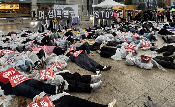 Protesters stage a die-in, a form of protest where demonstrators lie on the ground as though dead, in front of Exit 10 of Gangnam Station on Seoul Metro Line 2 in Gangnam District, southern Seoul, on May 18. [YONHAP]