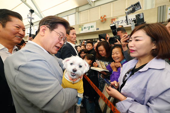 Democratic Party presidential candidate Lee Jae-myung greets a supporter's pet dog at a market in Gangjin County, South Jeolla, on May 11. [YONHAP] 