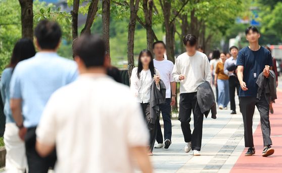 People stroll along the Cheonggyecheon, a stream that flows through central Seoul, on May 20 with their jackets slung over their arms. [YONHAP]