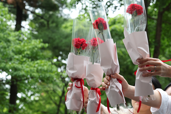 Elementary school teachers at Nowon District, northern Seoul, lift up flowers they received from students on Teachers' Day, which falls on May 15 in Korea. [NEWS1] 