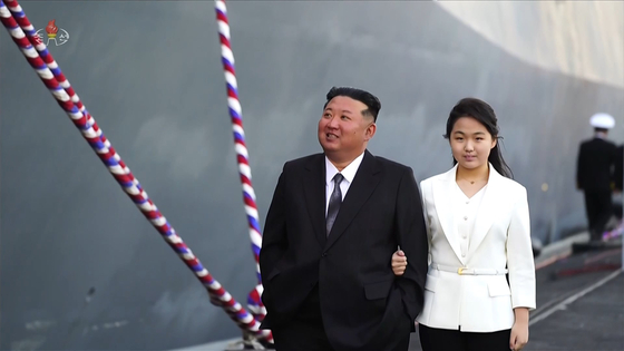 North Korean leader Kim Jong-un and daugher Kim Ju-ae walk along the Choe Hyun, a new 5,000-ton destroyer, during its launching ceremony at the Nampho Shipyard on the west coast, on April 26. [NEWS1]