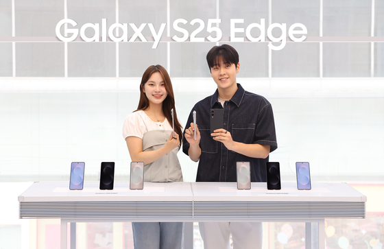Models hold up the new Samsung Galaxy S25 Edge models in southern Seoul on May 23. [SAMSUNG ELECTRONICS]