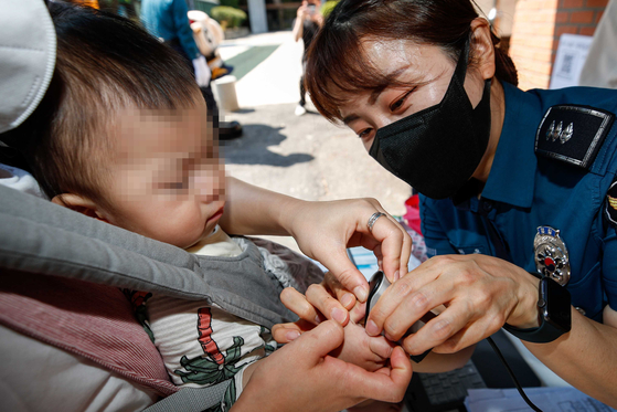 A police officer takes the fingerprints of a baby in Jongno District, central Seoul, on May 24, 2022, a day ahead of the national Missing Children's Day. [YONHAP]