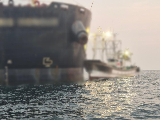A cargo ship, left, and a fishing boat remain lodged together after a collision on May 26. [COAST GUARD]