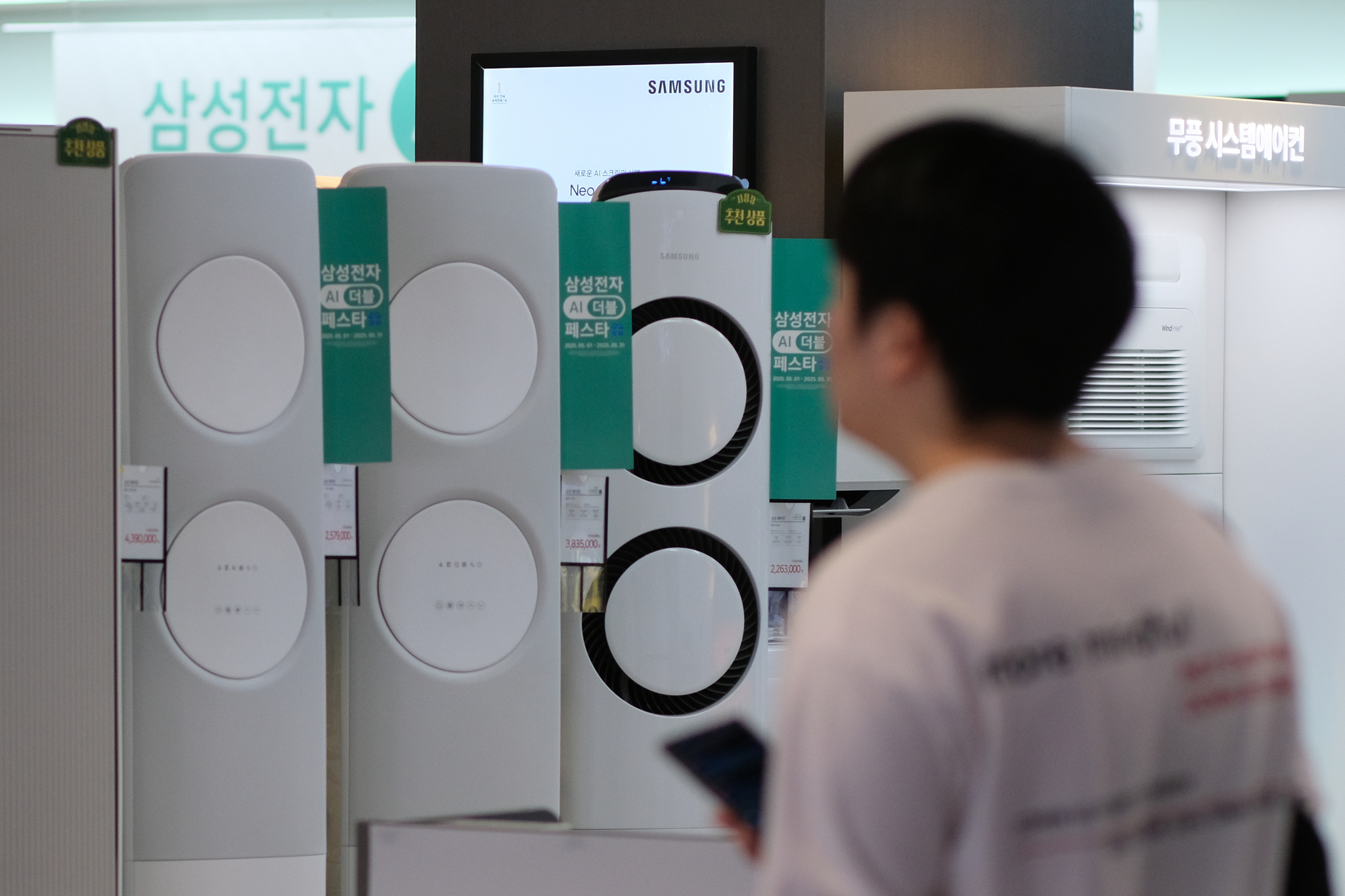 A customer looks at air conditioners on display at a retail store in Seoul on May 25 amid hot weathers continuing through the month. [YONHAP]