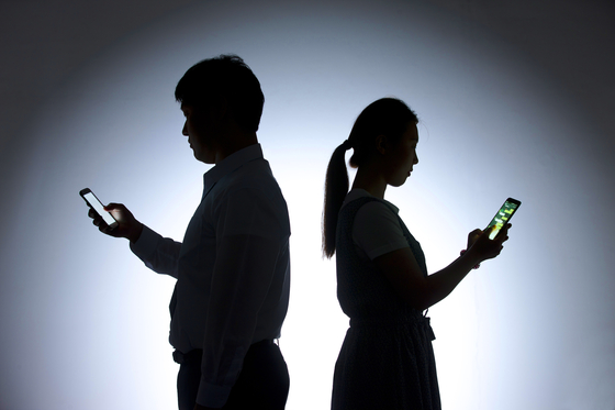 A man and a woman are on their phones [JOONGANG ILBO]