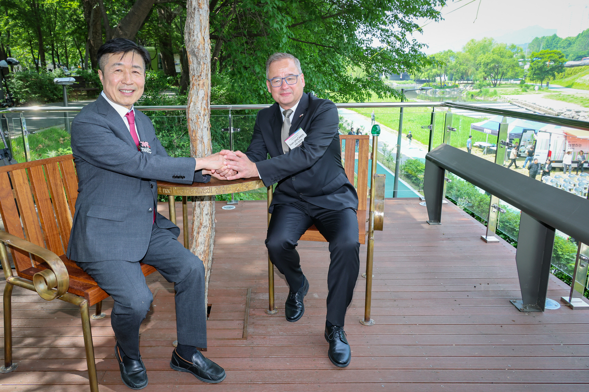 Ivan Jančárek, ambassador of the Czech Republic to Korea, right, and Jun Sung-soo, the head of Seocho District Office, sit and chat on the new Václav Havel’s memorial bench honoring the Czech democracy icon installed by the Yangjae Stream in the district, southern Seoul, on Monday. [SEOCHO DISTRICT OFFICE]
