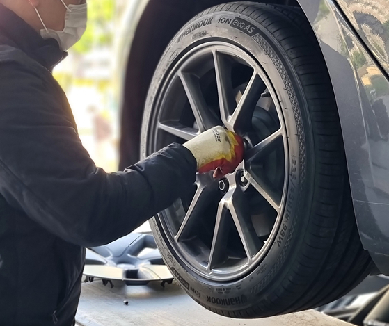 A mechanic at Hankook Tire's T'Station store installs the iON evo AS, a tire designed specifically for EVs, on a Tesla Model 3. [HANKOOK TIRE]