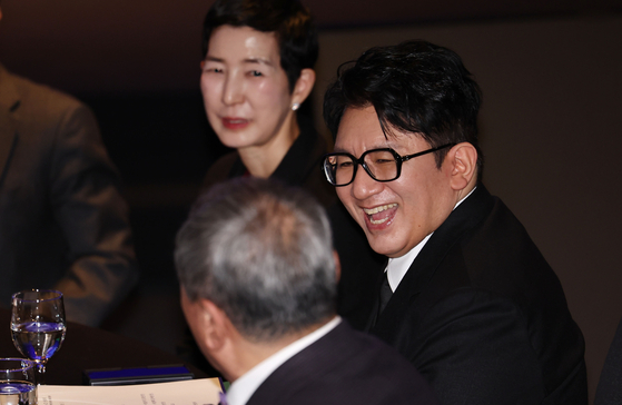 HYBE founder and chairman Bang Si-hyuk speaks with other guests at the 64th annual general meeting of the Federation of Korean Industries in western Seoul on Feb. 20. [YONHAP]