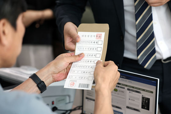 An election official hands a ballot to a voter on the first day of early voting for the 21st presidential election in Gwangju on May 29. [NEWS1]