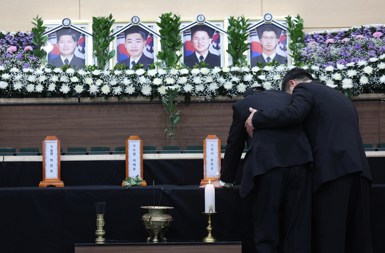 Grieving family members weep in front of the portraits of the four victims of the Navy patrol aircraft crash at the joint memorial altar, set up at the Navy Air Command gymnasium in Pohang, North Gyeongsang, on May 30. [YONHAP]