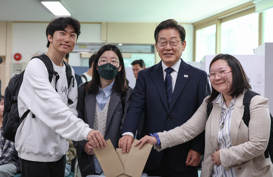Democratic Party candidate Lee Jae-myung, third from left, casts his ballot during early voting on May 29 with three young voters in Sinchon in Seodaemun District, western Seoul, where multiple universities are located. [KIM SUNG-RYONG]