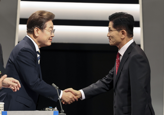 Presidential candidates Lee Jae-myung of the Democratic Party, left, and Kim Moon-soo of the People Power Party shake hands ahead of the second televised debate at KBS headquarters in Yeongdeungpo District, western Seoul, on May 23. [NEWS1]