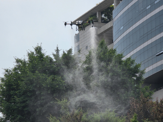 A drone carrying mosquito repellent smoke fly above the Daechi Reservoir Sports Park in Gangnam District, southern Seoul, spraying the repellent into the park on May 29. [JOONGANG ILBO]