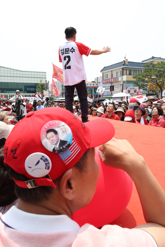 A person wearing a pin of former President Yoon Suk Yeol listens to People Power Party presidential candidate Kim Moon-soo give a speech in Gimhae, South Gyeongsang, on May 25. [JOINT PRESS CORPS]