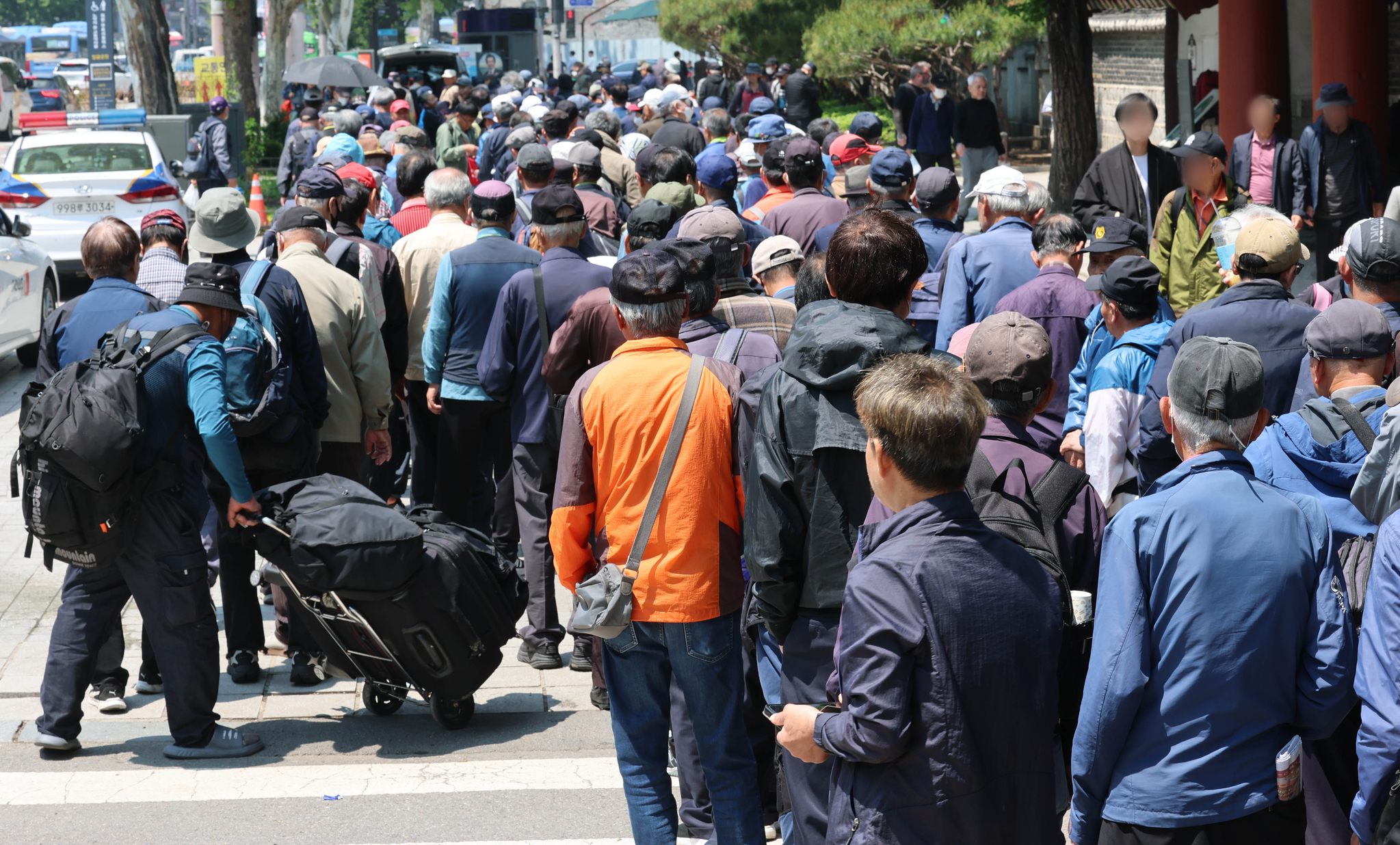 Elderly citizens wait in line for the free meal distribution at the Tapgol Park in Jongno District, central Seoul, on May 12. [NEWS1]
