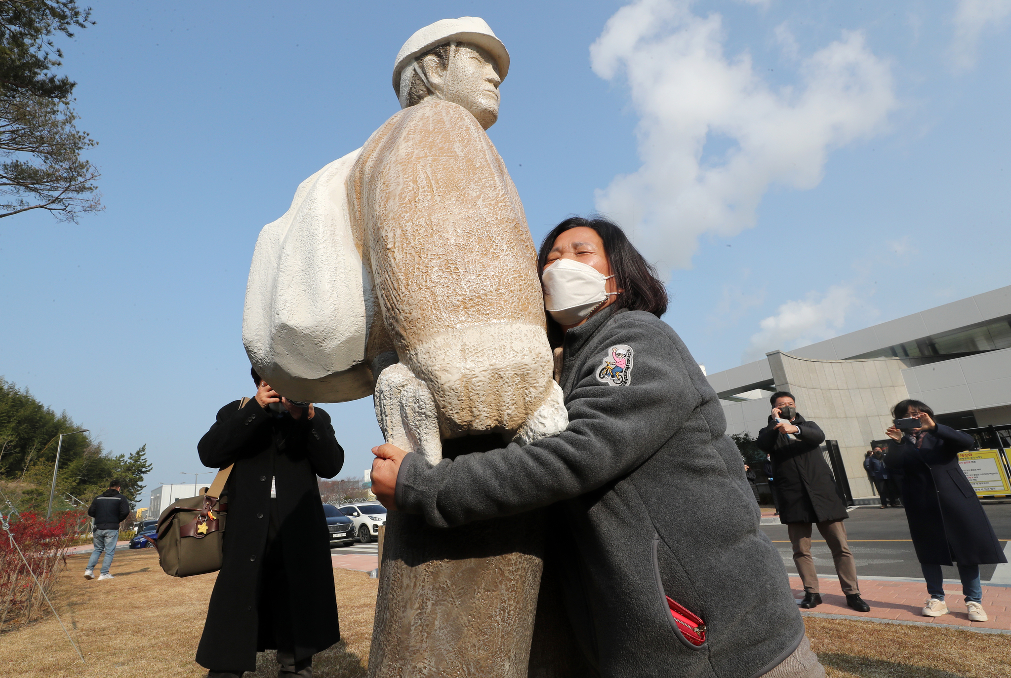 The mother of 25-year-old Kim Yong-gyun, a non-regular subcontracted worker who died at the Taean Thermal Power Plant in South Chungcheong on Dec. 11, 2018, holds a statue of her son set up outside the plant on Dec. 7, 2021. [YONHAP]