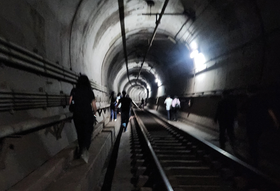 Passengers evacuate through an underground tunnel after a fire broke out on a Seoul Metro Line No. 5 train on May 31. [YONHAP]