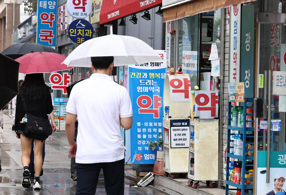 Pedestrians pass by pharmacies and clinics in central Seoul. [NEWS1]