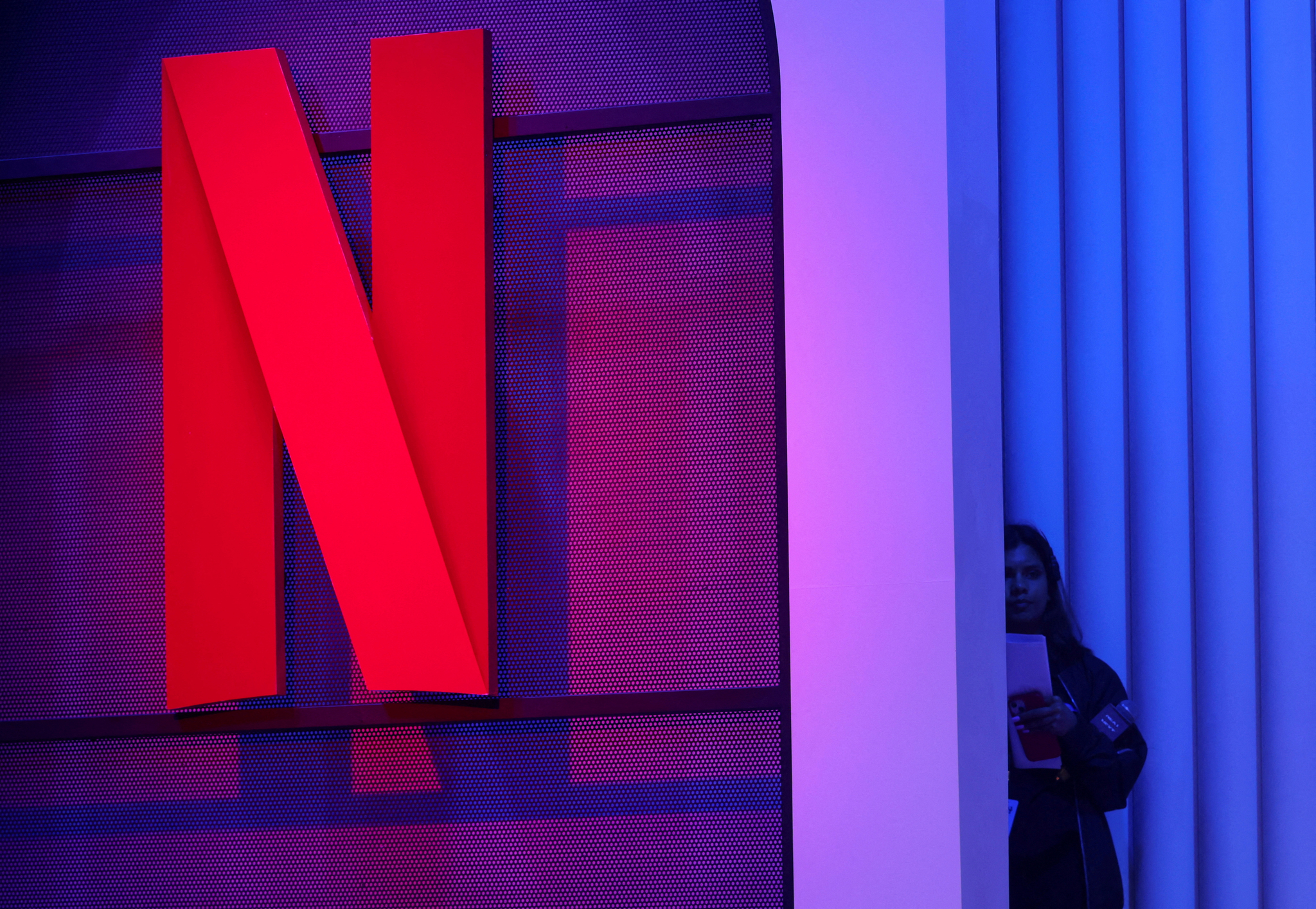 A woman stands next to a logo of Netflix during an event in Mumbai, India, Feb. 29, 2024. [REUTERS/YONHAP]
