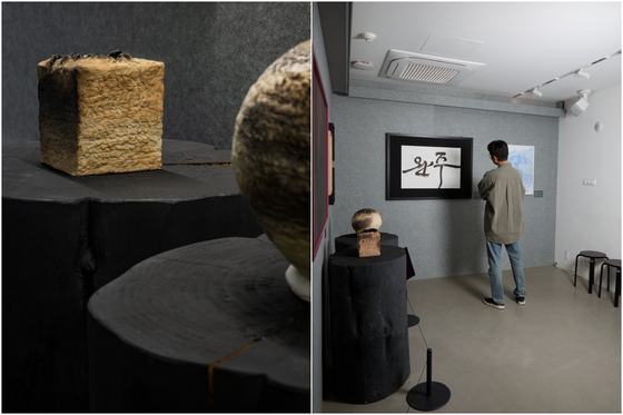 Ceramics by artist Jeong Ha-hyeon, left, and actor Park Jeong-min looks at works by calligrapher Kim So-young at the ″Wanju:Record:01″ exhibition at the LCDC Seoul in Seongdong District, eastern Seoul [LCDC SEOUL]
