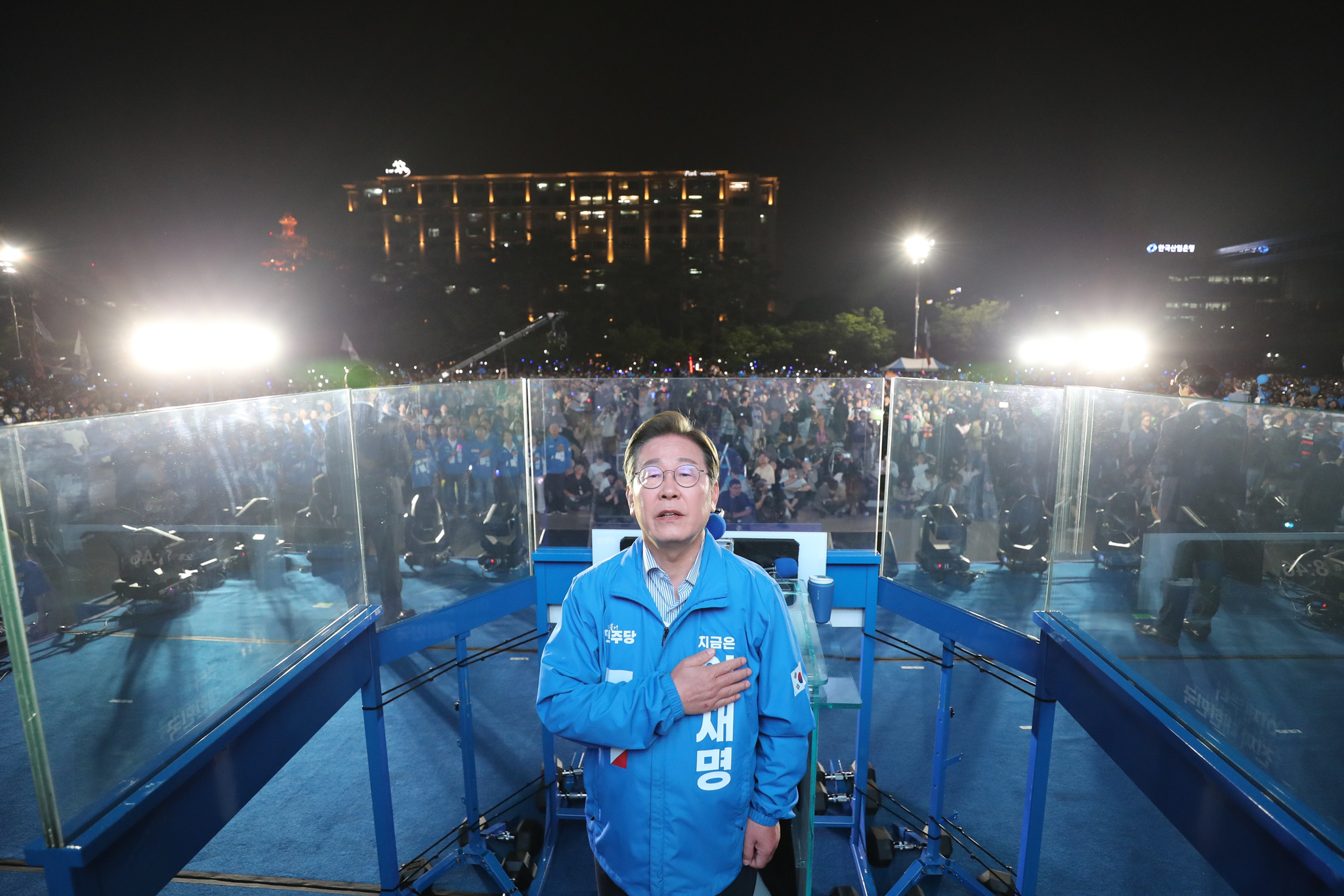 Lee Jae-myung of the liberal Democratic Party, the newly elected president, sings the Korean national anthem at his final rally site in Yeouido, western Seoul, on June 2, a day ahead of the election. Bullet-proof glass panels are seen to shield Lee from threats. [KIM SEONG-RYONG]