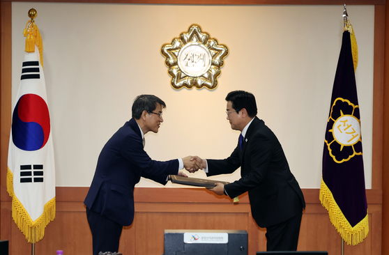 Rho Tae-ak, chairperson of the National Election Commission (NEC) at left, gives the NEC's certification over to Democratic Party floor leader Park Chan-dae, confirming Lee Jae-myung as the president-elect of Korea on June 4 in Gwacheon, Gyeonggi. [NEWS1]