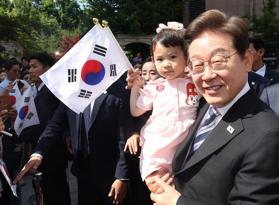 President Lee Jae-myung holds up a baby in front of their home in Gyeyang District, Incheon, on June 4. [JOINT PRESS CORPS]