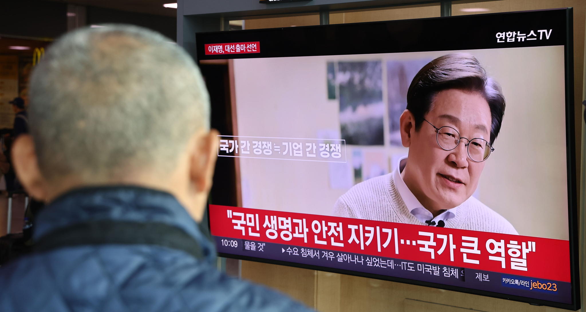 A passerby watches a video of Democratic Party candidate Lee Jae-myung announcing his bid for the June 3 presidential election at Seoul Station in central Seoul on April 10. [YONHAP]
