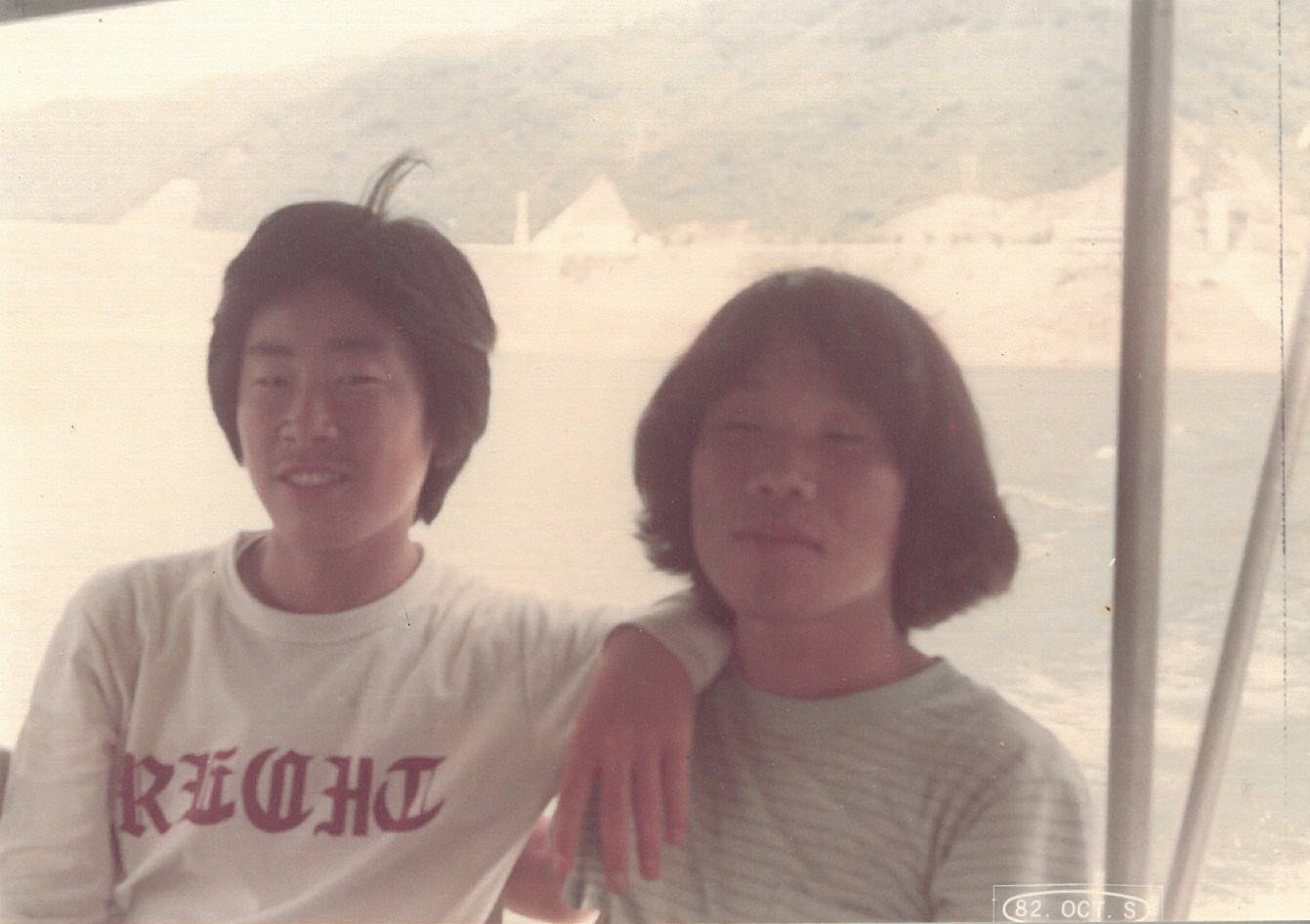 President Lee Jae-myung, left, takes a commemorative photo with his childhood friend Shim Jeong-woon on a boat along the Soyang River en route to Yanggu, Gangwon, during a hiking trip in 1982 while they were students at Chung-Ang University. [SHIM JEONG-WOON]