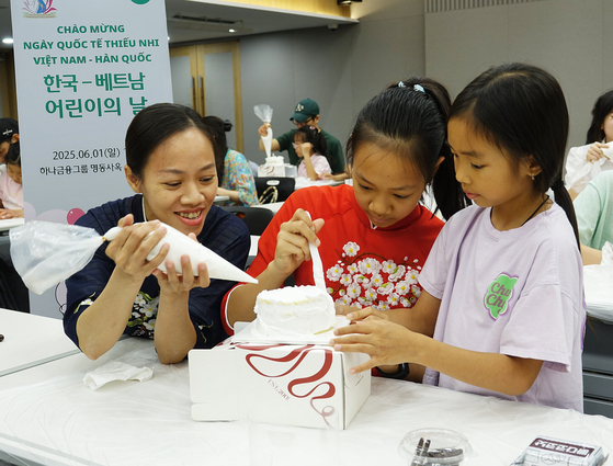 Families from multicultural households of Vietnamese background decorate cakes during a hands-on activity at Hana Bank’s Myeong-dong office in central Seoul on June 1. [YONHAP]