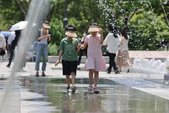 Children cool off under a fountain tunnel in Gwanghwamun Square in Jongno District, central Seoul, on June 5. [YONHAP]