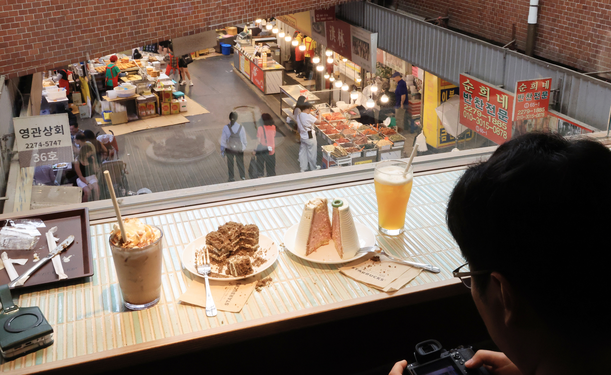 A visitor at Starbucks’ new Gwangjang Market branch on May 29 sits by the window, which overlooks the market. [YONHAP]