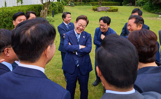 President Lee Jae-myung laughs with the Democratic Party (DP) leadership on the lawn of the presidential residence in Hannam-dong, Yongsan District, central Seoul on June 7 for dinner. It was the first time that the president had met lawmakers from the DP in a formal setting since his inauguration on June 4. ″It is our duty to live up to the expectations of the citizens who elected us,″ he said.