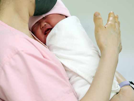 A newborn is seen in the arms of a nurse at a hospital in Guro District, western Seoul on May 28. [NEWS1] 