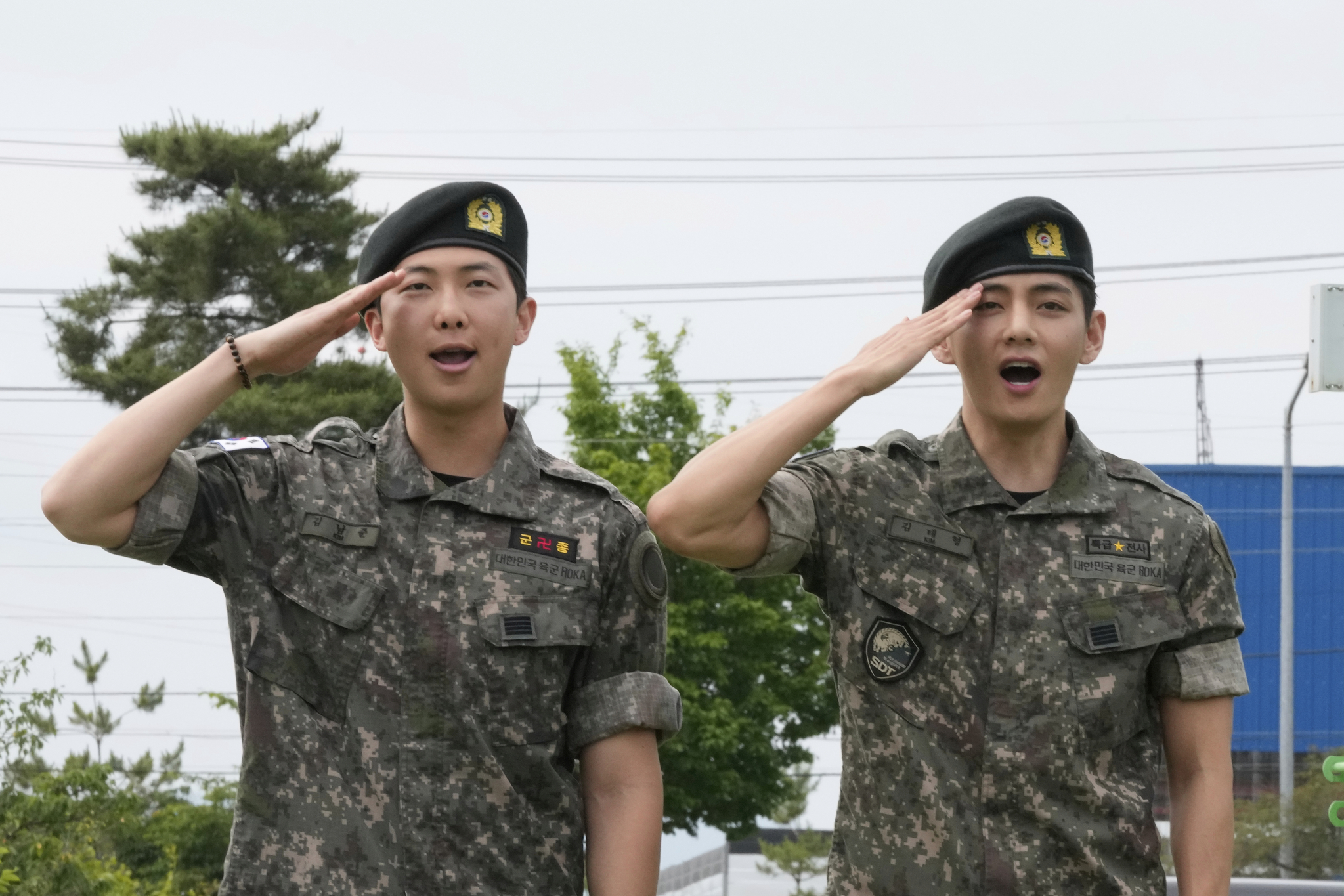 K-pop band BTS members RM, left, and V salute after being discharged from a mandatory military service in Chuncheon, Gangwon, on June 10, 2025. [AP/YONHAP]