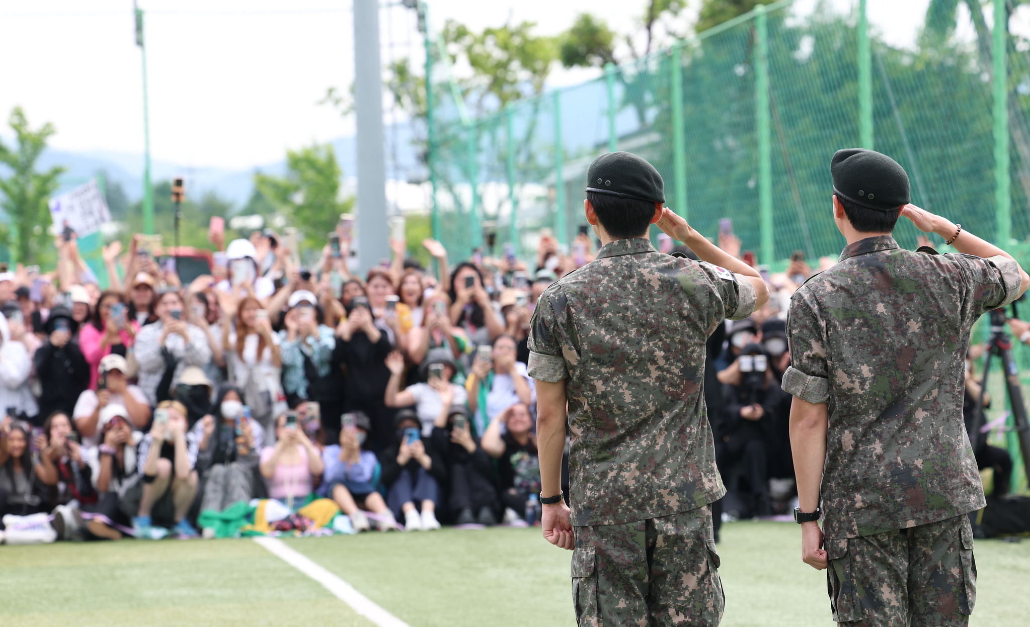Members RM, left, and V of boy band BTS salute to fans after finishing their military duties on June 10 in Gangwon. [NEWS1]